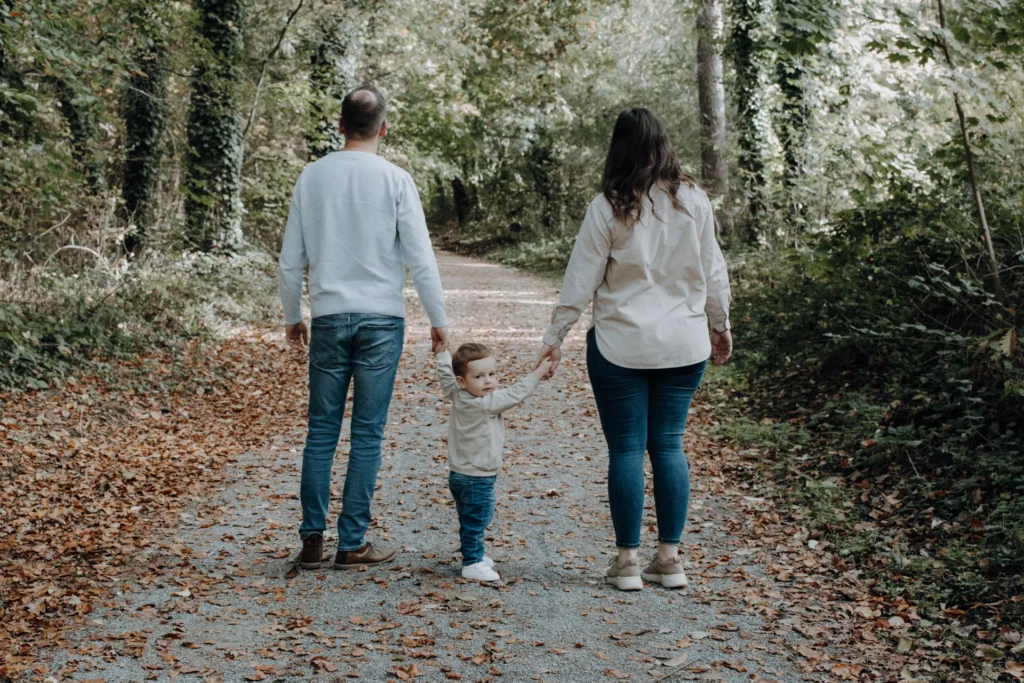 Familienfotografie in Karlsruhe. Vater und Mutter spazieren mit ihrem Sohn durch den Wald