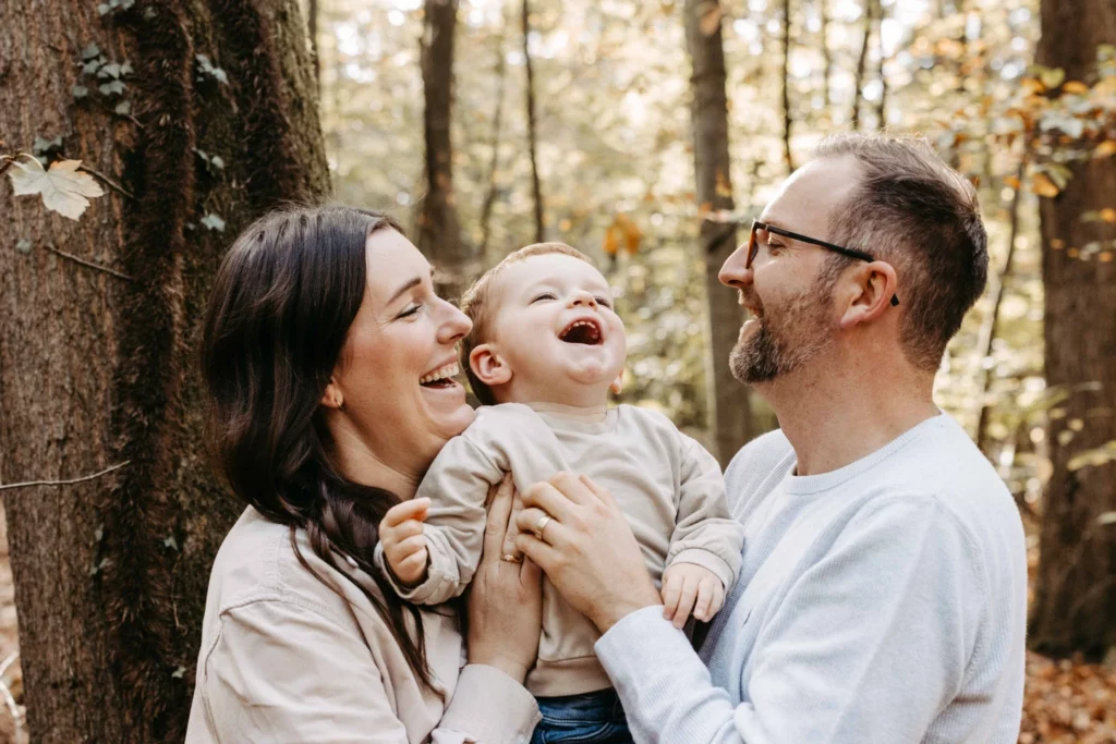 Vater und Mutter halten Ihren Sohn gemeinsam hoch und lachen
